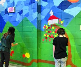 A pair of Highlands students work on a hallway mural as part of art class.