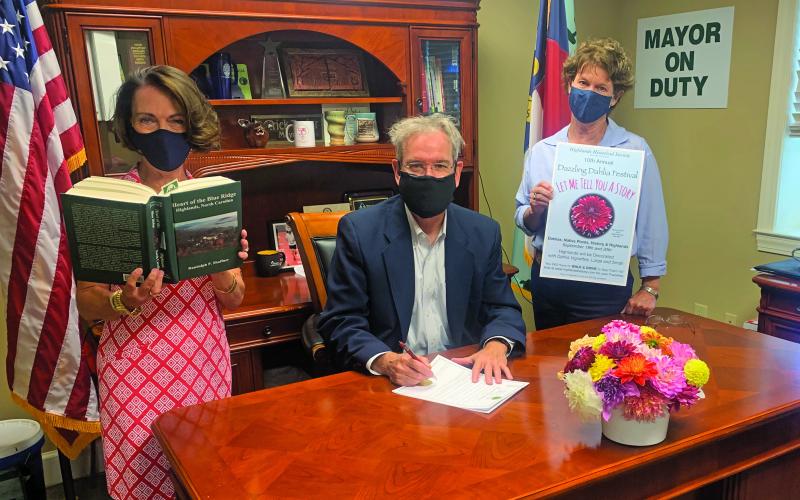 Highlands Mayor Patrick Taylor signs a proclamation celebrating this weekend’s 10th annual Dahlia Festival. From left, Kim Daugherty holding the book, Taylor and Lisa Dailey.