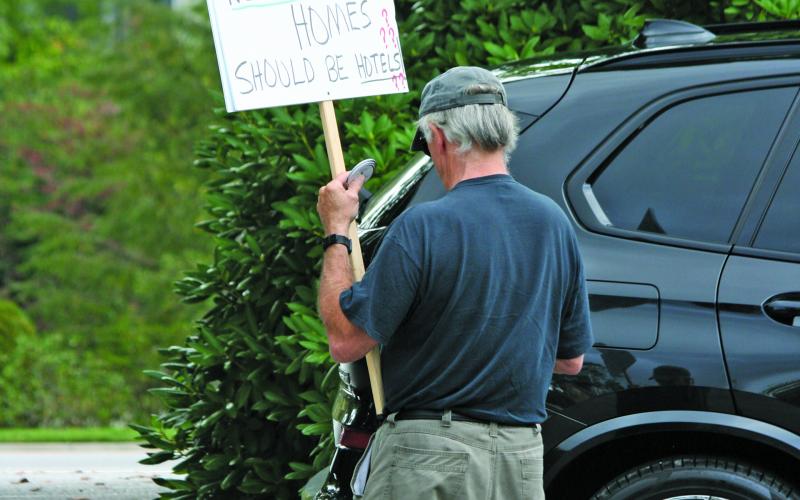 An advocate for eliminating short term rental units in residential zones carries a homemade sign outside a public hearing on Thursday, Aug. 25.