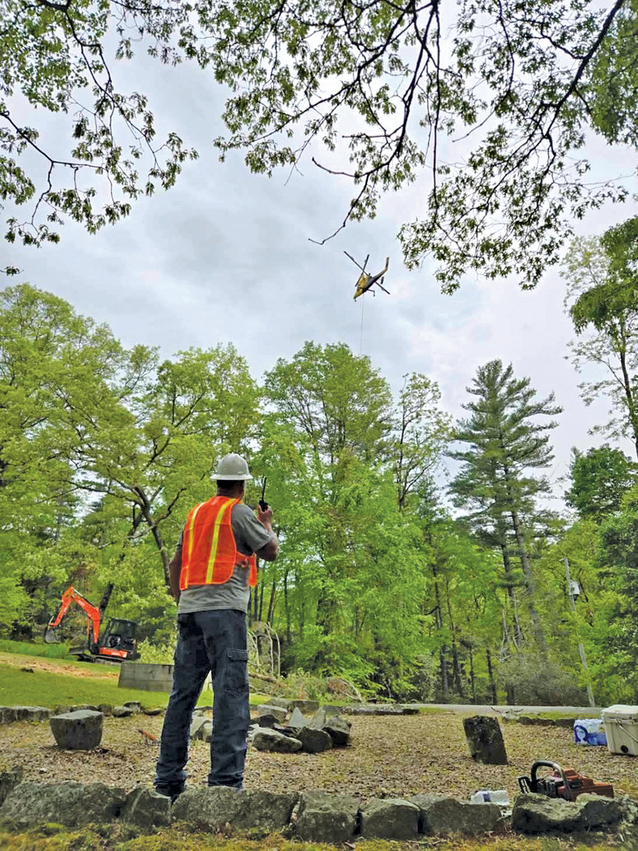 Tree removal via helicopter requires precision and constant communication.