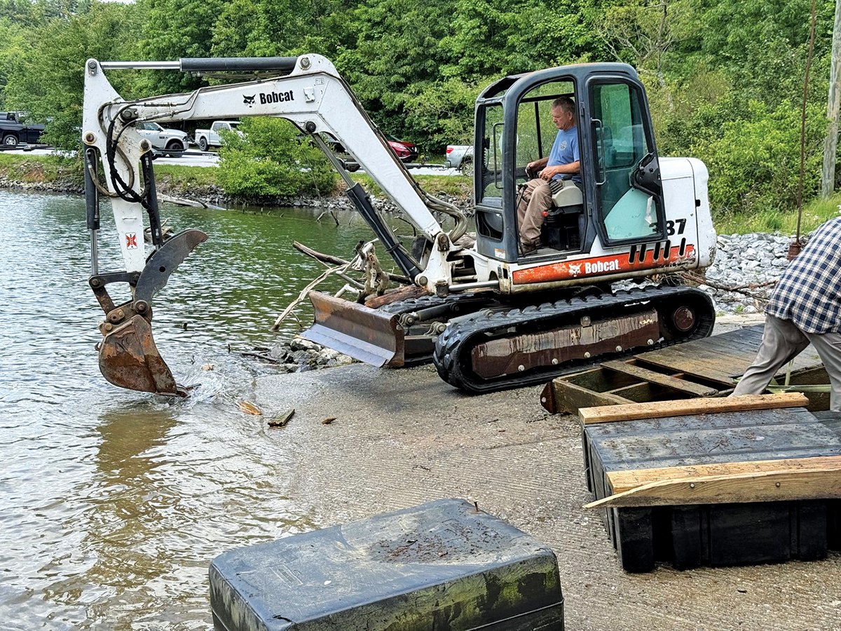 A backhoe is used to remove wooden debris from the lake.