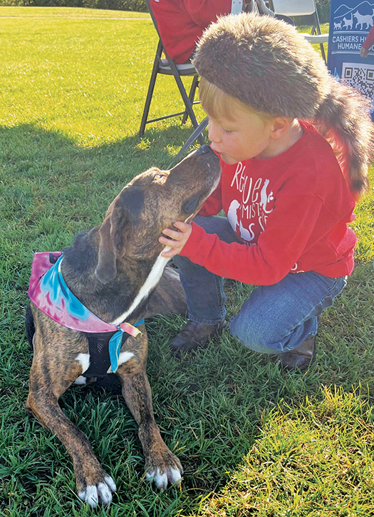 CHHS shelter dog Clyde receiving a kiss from a young Blessing of the Animals attendee.