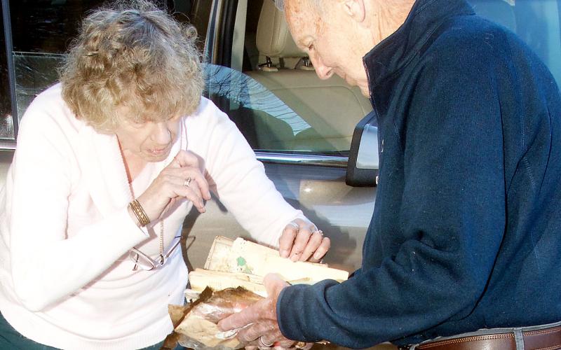 Ann and Joseph Scott look over items good Samaritans working at a neighbor’s farm had dug out of the charred rubble of the couple’s home for them. The papers were partly burned and water-soaked, but some could be salvaged. (Photo by Don Richeson.)