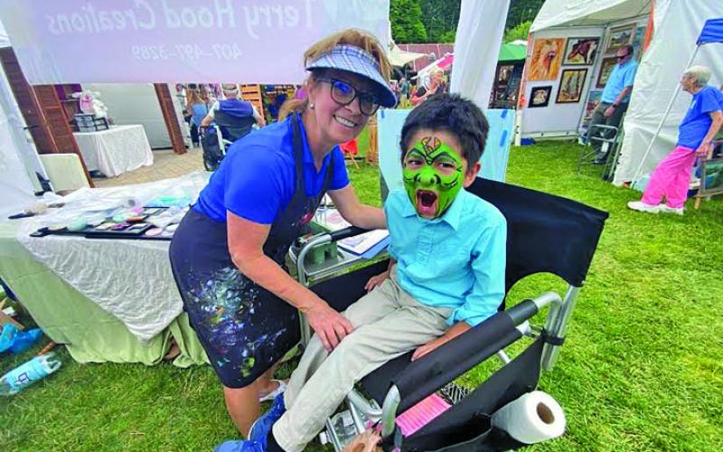Photo by Christopher Smith/Staff Terry Hood painted a face on Jacob at the Mountaintop Arts and Crafts Show in June.