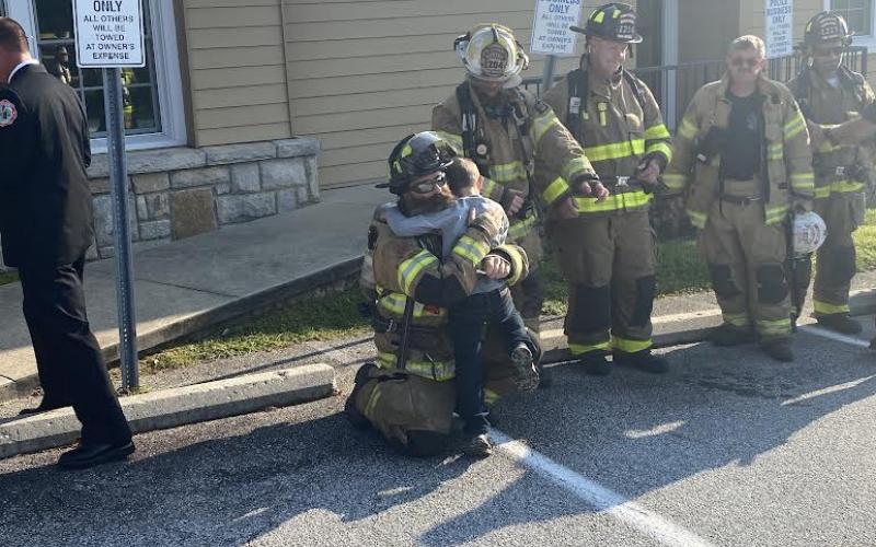 Photo by Christopher Smith/Staff A Highlands firefighter gets a hug from his son after the walk.