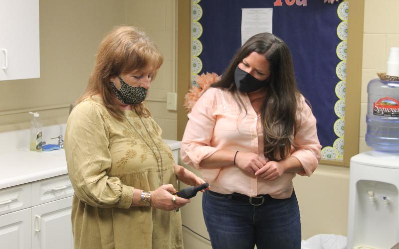 Photo by Christopher Smith/Staff Ghost Hunters of Asheville owner Pepper Paris teaches Center for Life Enrichment director Fallon Hovis how to use an EMF detector.