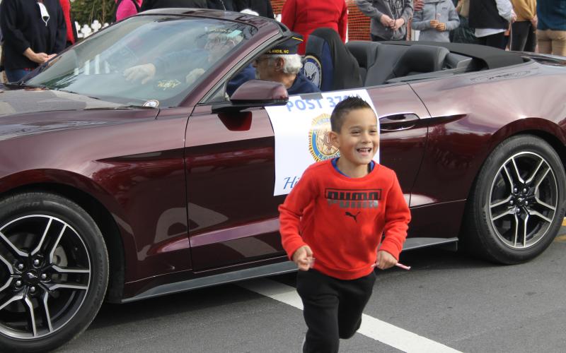 Photo by Christopher Lugo/Staff A kid runs from a car after getting candy.