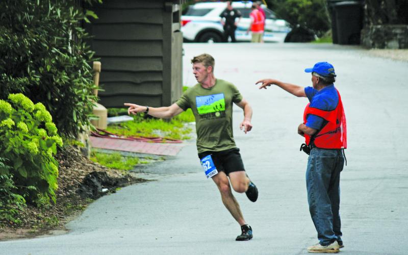 Rotarian Jim Oesterle (right) directs a runner which way to turn during the Rotary Club of Highlands Twilight 5k.