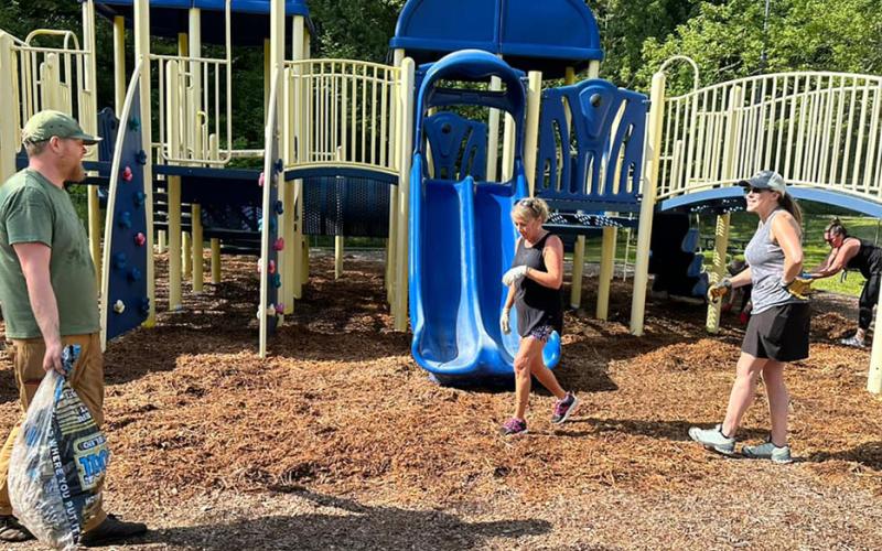 Volunteers spread fresh mulch under the playground equipment at Highlands School on Aug. 12.
