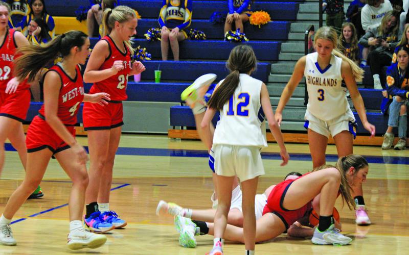 Highlands and West Oak players hit the deck to grab a loose ball during their game on Friday night. The Warriors seized a 45-34 victory.
