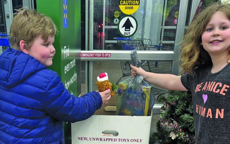 A pair of children donate to “Toys for Tots” during the annual Shop with a Cop event held at Walmart in Franklin.
