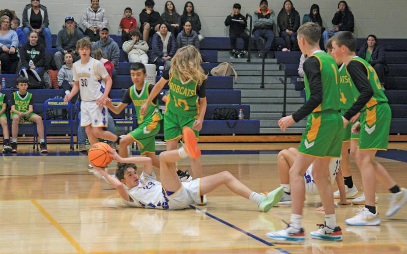 Highlands’ Charlie Wilkes (23) looks for an open teammate while sitting on his backside.