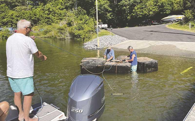 Photo courtesy of Marianne Smith - Volunteers help unwrap the rope used to transfer floating docks to shore, where they are lifted by Bryan Simon’s crane.