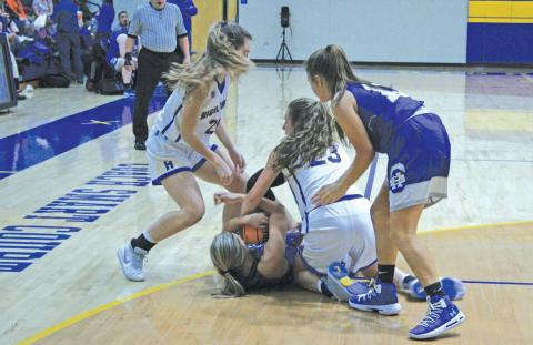 Highlands’ players Jordan Carrier (23) and Jeslyn Head (22) get on the floor to tie up a Hiwassee Dam player for a jump ball during their game on Friday night. Highlands won the contest 54-48.