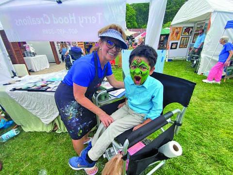 Photo by Christopher Smith/Staff Terry Hood painted a face on Jacob at the Mountaintop Arts and Crafts Show in June.