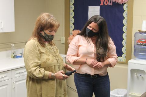 Photo by Christopher Smith/Staff Ghost Hunters of Asheville owner Pepper Paris teaches Center for Life Enrichment director Fallon Hovis how to use an EMF detector. 