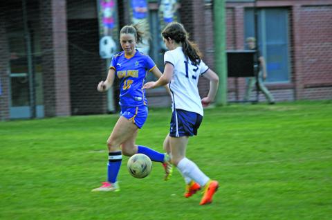 At the home game Thursday, April 18, Senior Mackenzie Woods runs to intercept the ball before an opponent.