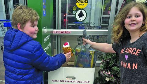 A pair of children donate to “Toys for Tots” during the annual Shop with a Cop event held at Walmart in Franklin.