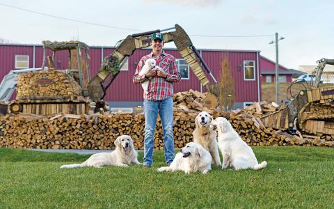 Joshua Crawford, accompanied by his golden retrievers, shows off his skid steer and crawler excavator firewood designs at the 2025 Cashiers Festival of Trees.  |  Photo courtesy of Chelsea Cronkite