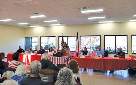 Candidates at the commissioners forum (from left) District 2 candidates Nick Lofthouse, David Culpepper, Dylan Castle and Kellie Burns; Republican Party Chair Patti Trick at the microphone; and District 1 candidates John Shearl, Joey Wilson and Don Willis.
