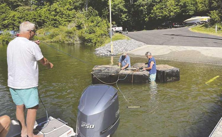 Photo courtesy of Marianne Smith - Volunteers help unwrap the rope used to transfer floating docks to shore, where they are lifted by Bryan Simon’s crane.