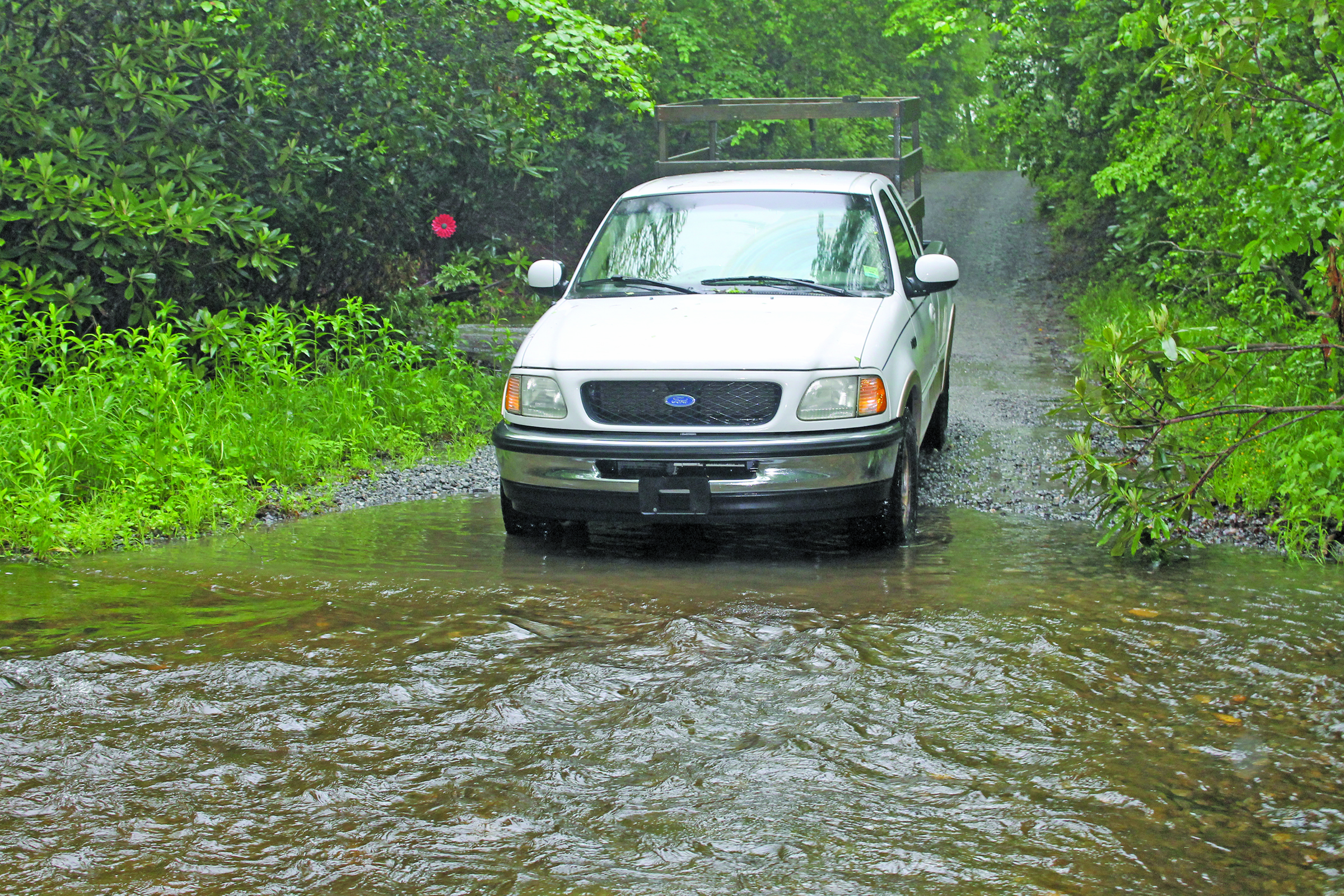 Photo by Christopher Lugo/Staff Duncan Greenlee trying to drive through the creek that runs across Hickory Knut Gap Road in Scaly Mountain. 