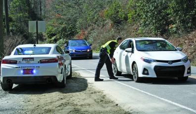 Highlands Police Department officer Tim Broughton stops drivers at a checkpoint along US 64 on Friday. The state of North Carolina is now under a “Stay at home” order and both Macon County and the Town of Highlands are urging residents to comply.
