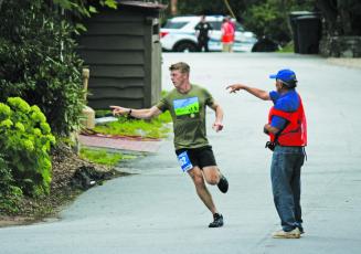 Rotarian Jim Oesterle (right) directs a runner which way to turn during the Rotary Club of Highlands Twilight 5k. 