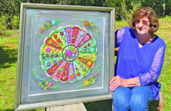 Local fiber artist Betty Cabe displays one of her quilling works prior to an exhibition.