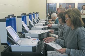 Election workers test equipment during a simulation.