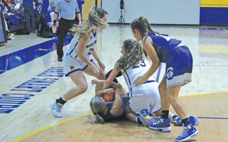 Highlands’ players Jordan Carrier (23) and Jeslyn Head (22) get on the floor to tie up a Hiwassee Dam player for a jump ball during their game on Friday night. Highlands won the contest 54-48.