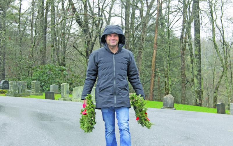 Photo by Christopher Lugo/Staff Volunteer Derek Taylor carries wreaths at Highlands Cemetery. 
